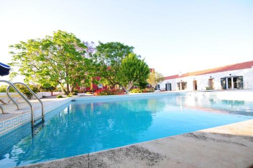 a large swimming pool with blue water at Hortas de Baixo, Luz de Tavira in Tavira