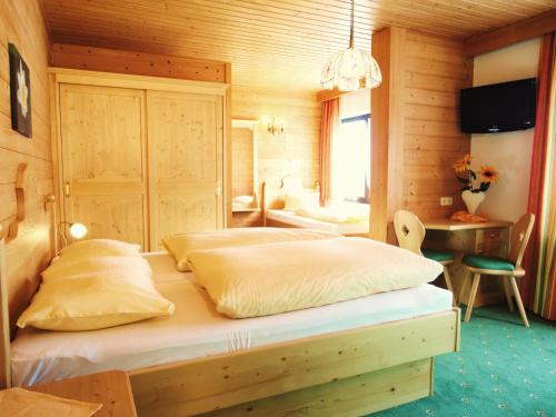 a bedroom with two beds in a wooden room at Alpenhof Schwaiger - Hotel Garni in Mühlbach am Hochkönig