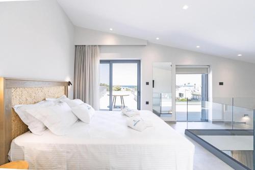 a white bedroom with a large bed with white pillows at Milva Mare Luxury Apartments in Kos