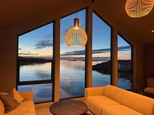 a living room with a couch and large windows at OceanView Karmoy Jacuzzi, Sauna & Sea Views in Karmøy