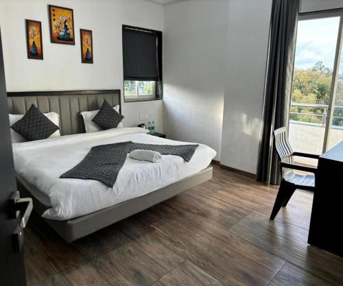 a bedroom with a bed and a desk and a window at Sunny Executive in Satara