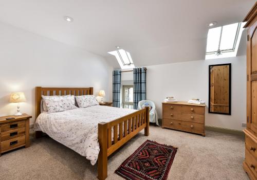 a bedroom with a bed and a dresser and a mirror at The Steading at Pitmeadow Farm in Dunning