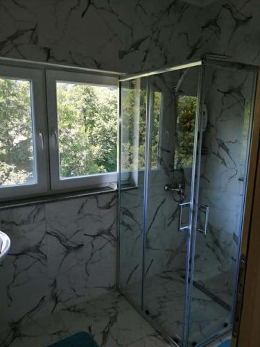 a bathroom with a glass shower with two windows at Sam guest house in Jajce