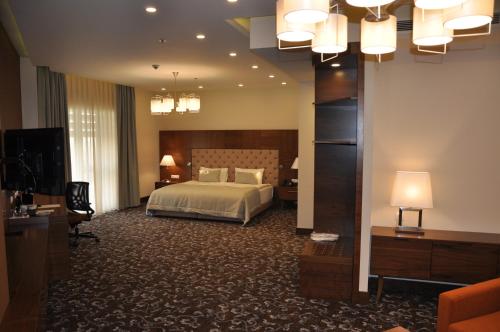 a large hotel room with a bed and a television at Kurmick Maysan Hotel in Amarah