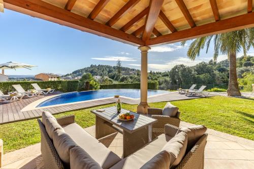 an outdoor patio with a table and chairs and a pool at Villa Nobleza, oasis con piscina y gimnasio a 2 min del centro in El Port de la Selva