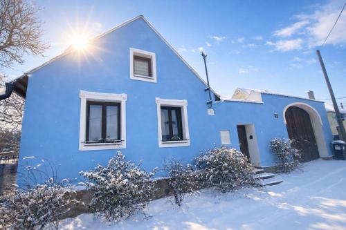 a blue house in the snow with the sun behind it at Chalupa Za Vraty Jevišovice in Jevišovice