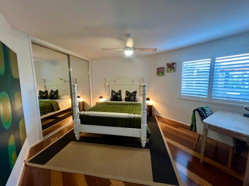 a bedroom with a green bed and a mirror at Perfect weekend getaway plus golf at your doorstep in Salamander Bay