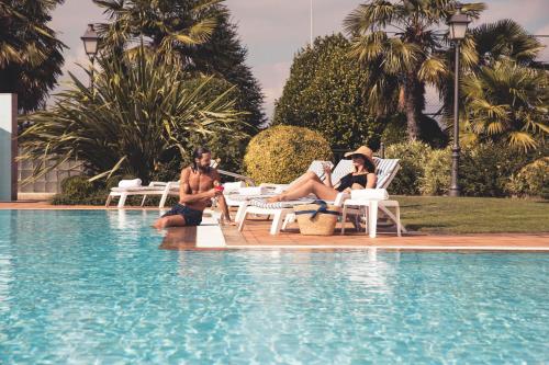 a group of people sitting next to a swimming pool at Gran Hotel Los Abetos in Santiago de Compostela