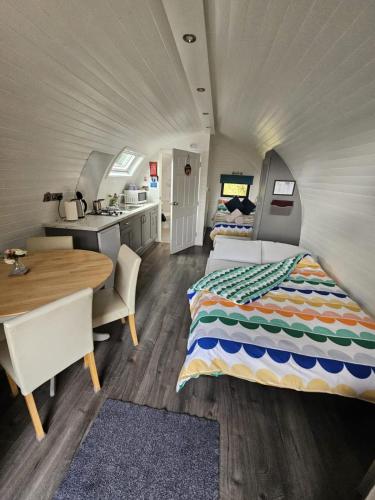 a bedroom with a bed and a kitchen and a table at Gortin Glen Glamping in Omagh