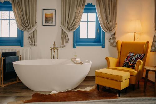 a bathroom with a large tub and a chair at Heritage Guesthouse in Bartoştana