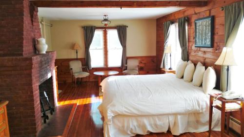 a bedroom with a white bed and a fireplace at Woodbound Inn in Rindge