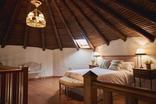 a bedroom with a large bed and a chandelier at ALOJAMIENTO TURISTICO- AGROTURISMO Dehesa La Pared in Chillón