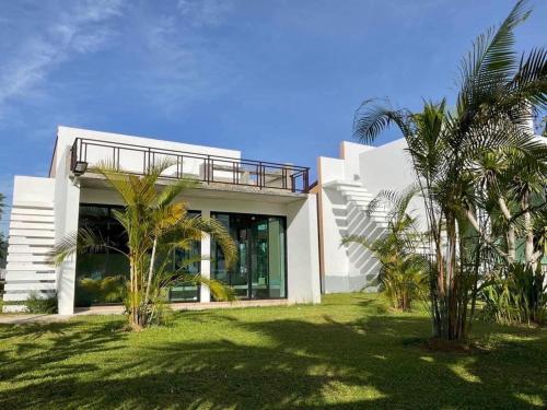 a white house with palm trees in front of it at F&F Poolvilla Beach Tha Chana in Suratthani