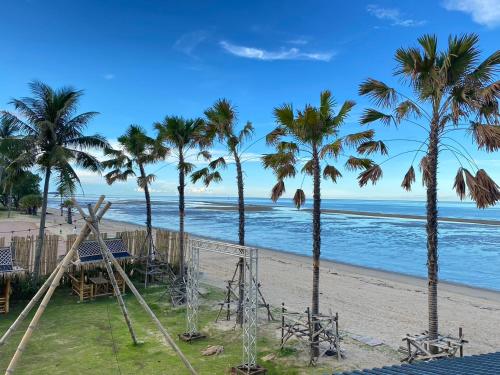 a beach with palm trees and a swing set at F&F Poolvilla Beach Tha Chana in Suratthani