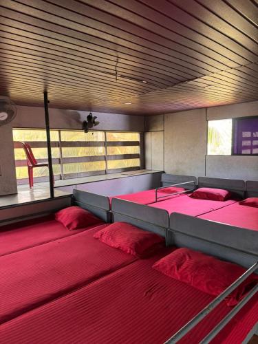 a group of beds in a room with red pillows at devanjana Guruvayur in Jāmb