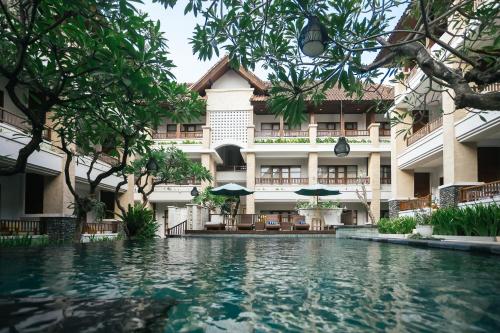 a swimming pool in front of a building at Fourteen Roses Beach Hotel in Legian