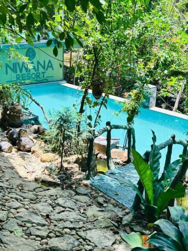 a swimming pool in a garden with plants at Niwana Resort in Ratnapura