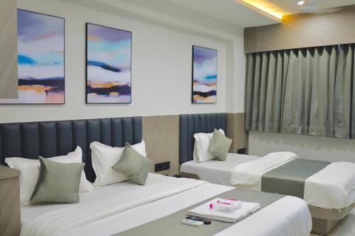 a hotel room with two beds and paintings on the wall at Hotel Palash Icon in Ahmedabad