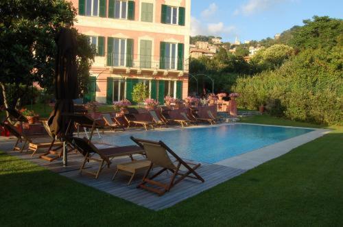 a pool with chairs and a table and a building at Villa Rosmarino in Camogli