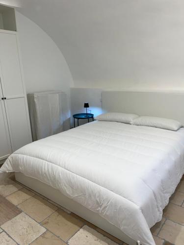 a white bed in a bedroom with a night stand at i GERMÅNI REALI in Scanno