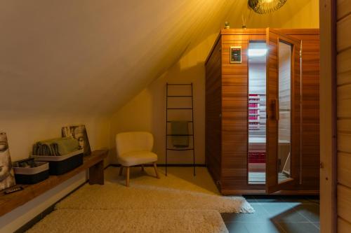 a attic room with a ladder and a chair at Vakantiewoning Pelterheggen in Grote Heide