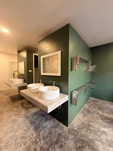 a bathroom with two sinks and a green wall at Cheevit Cheeva Koh Tao Hostel in Ko Tao