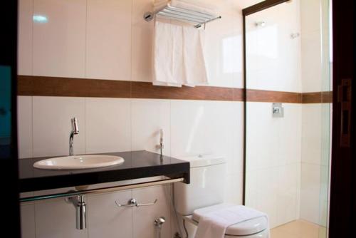a white bathroom with a sink and a toilet at Lis Hotel in Teresina