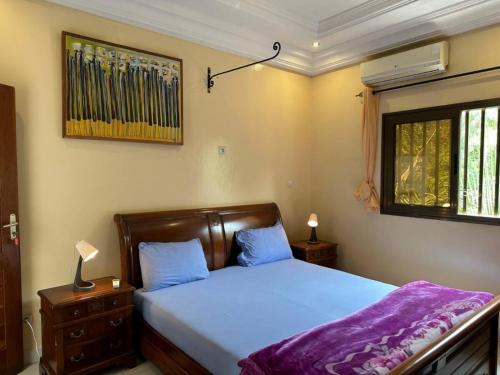 a bedroom with a bed with blue sheets and a window at Tekrour- la case des hôtes- Suite privée-chambre, salon et cuisine complete in Mbour
