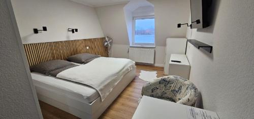 a small bedroom with a bed and a chair at Hotel Pelikan in Papenburg