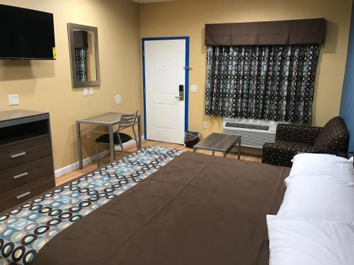 a hotel room with a bed and a living room at Deluxe Inn & Suites - Baytown in Baytown