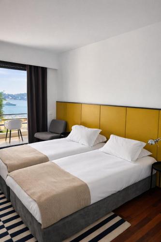 a hotel room with two beds and a window at Hôtel Le Versailles in Villefranche-sur-Mer
