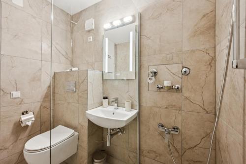 a bathroom with a sink and a toilet and a shower at Ramoni Apartments - Abendgold in Enzklösterle