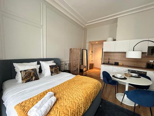 a bedroom with a bed and a table and a kitchen at Le Chic, en hypercentre au calme in Limoges