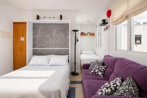 a living room with a purple couch and a window at Ático la Azotea con terraza PRIVADA in Seville