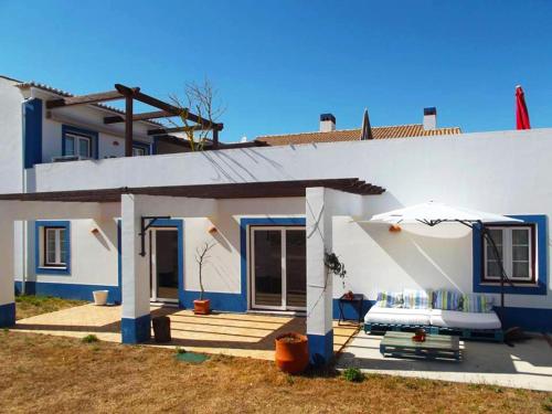 a blue and white house with a patio with an umbrella at Herdade Alem Santos in Lousal
