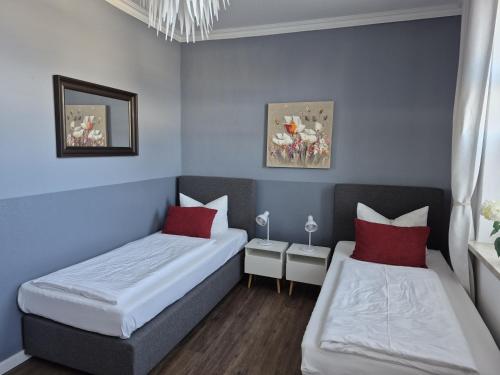 two beds in a room with blue walls and red pillows at City-Apartment 1 in Bernburg