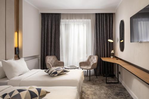 a hotel room with two beds and a desk at Hotel Soimul in Poiana Brasov