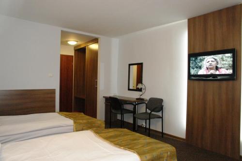 a hotel room with a bed and a tv on a wall at Hotel Junior in Zamość