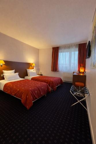 two beds in a hotel room with red sheets at Logis Hôtel Restaurant La Palette in Wettolsheim