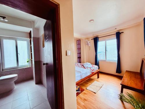a bedroom with a bed and two windows and a bathroom at Perched on a mountain top, breathtaking city view in Kathmandu