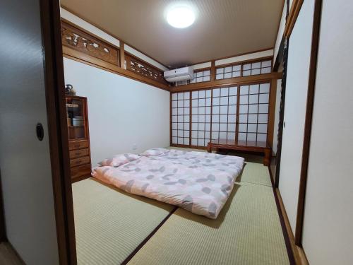 a small room with a bed in the corner of a room at Daizaifu Guest House 1 in Dazaifu