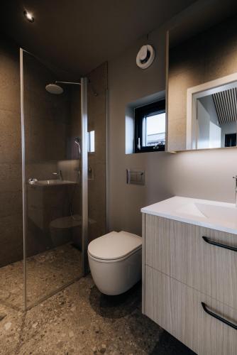 a bathroom with a toilet and a shower and a sink at Green Geysir Cottage in Torfastaðir