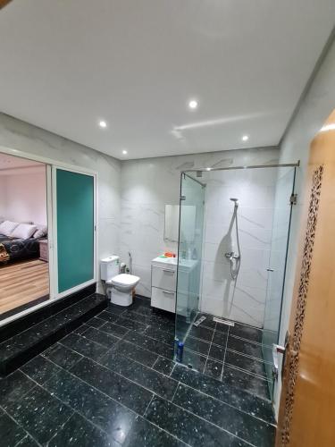 a bathroom with a glass shower and a toilet at Adnani in Temara
