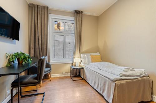 ein Schlafzimmer mit Bett, Schreibtisch und Fenster in der Unterkunft Strandgata Hotel in Haugesund