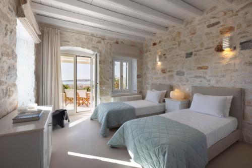 a bedroom with two beds and a stone wall at Villa Caelia in Santa Maria