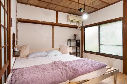 a bedroom with a large bed with purple sheets at FLORAhouse in Oita
