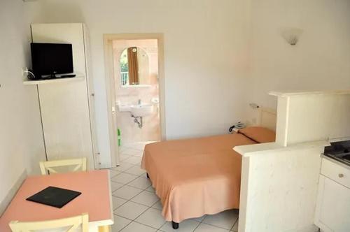 a bedroom with a bed and a table and a sink at Palm Village in Villasimius