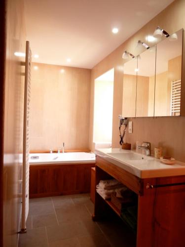une salle de bain avec une baignoire et un lavabo et une baignoire dans l'établissement Chambres d'Hôtes du Hameau Les Brunes, à Bozouls