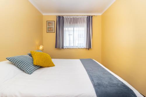 a bedroom with a large bed with yellow walls and a window at Coast 2 Bedroom Apart Setúbal 45 min from Lisbon in Setúbal