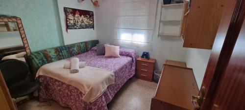 a bedroom with a bed with purple sheets and a chair at Apto Templo de Isis, Habitación Verde en Amate in Seville